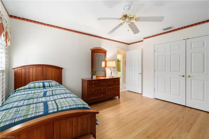 Bedroom with a closet, light hardwood / wood-style floors, ceiling fan, and crown molding