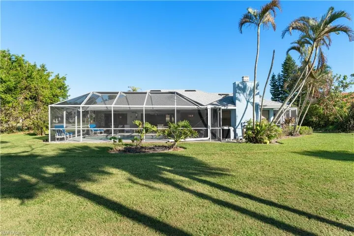Rear view of property featuring a lanai and a lawn