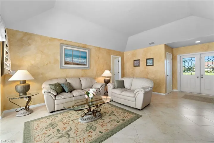 Tiled living room featuring french doors and lofted ceiling
