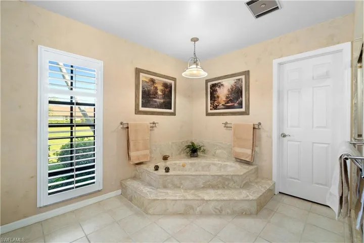 Bathroom featuring tile patterned flooring, a wealth of natural light, and tiled bath