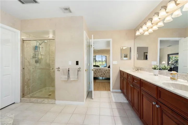 Bathroom with tile patterned floors, vanity, walk in shower, and a wealth of natural light