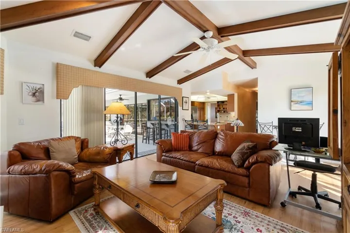 Living room with lofted ceiling with beams and light hardwood / wood-style floors