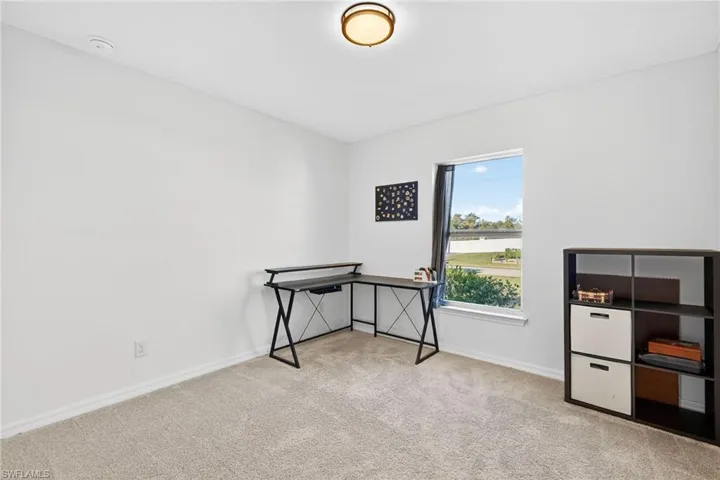Home office featuring a water view and light carpet