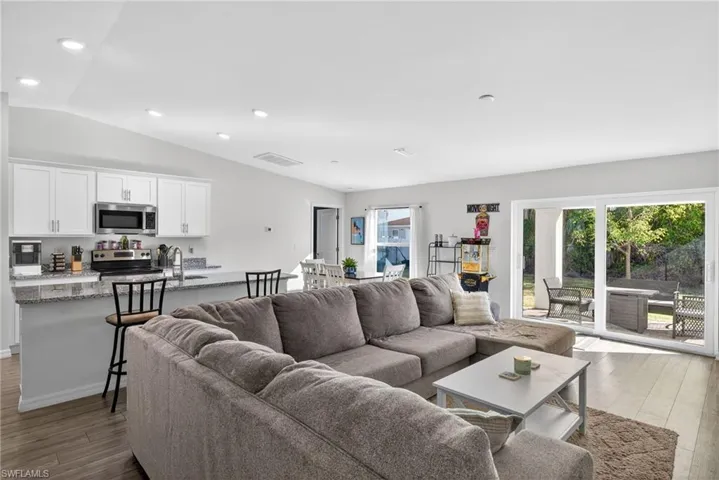 Living area with dark wood-style floors and vaulted ceiling