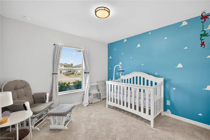 Bedroom with a nursery area, carpet, and an accent wall