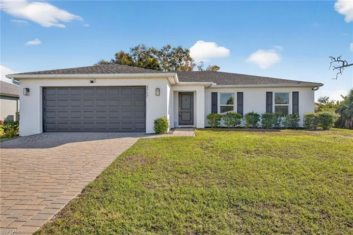 Single story home with stucco siding, a front lawn, decorative driveway, and a garage