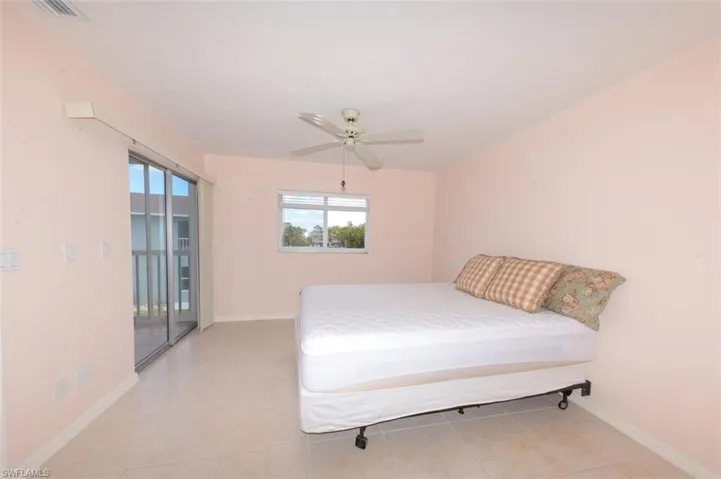 Primary bedroom suite with large tile flooring, updated window and sliding glass doors leading to lovely Lanai.