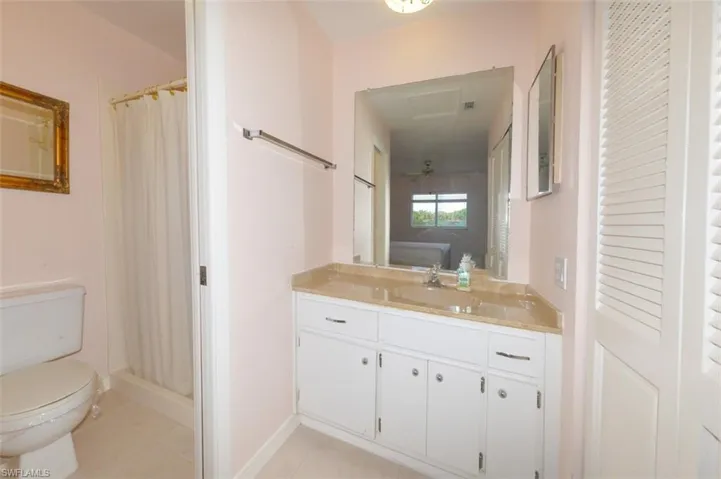 Primary bedroom suite bathroom with door to shower and commode on left and closet on right.