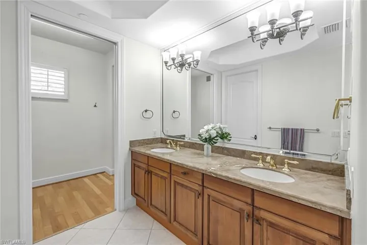 Bathroom featuring double vanity, light tile patterned floors, and a chandelier