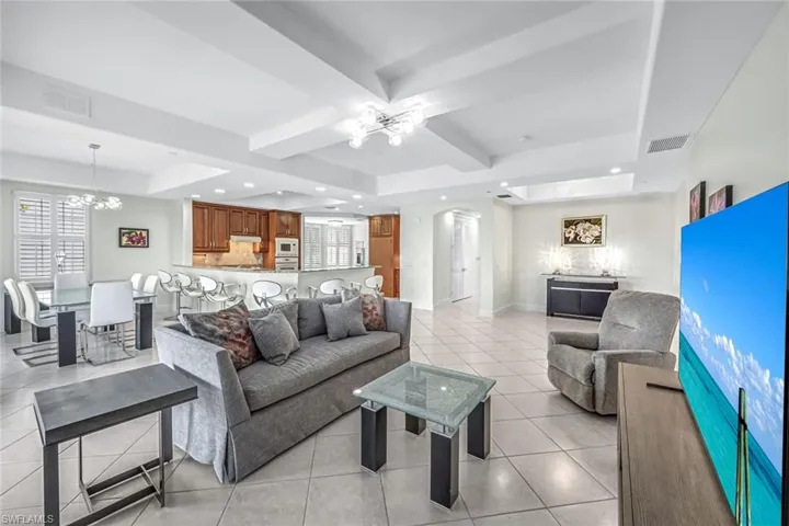 Living room featuring a chandelier, beamed ceiling, light tile patterned floors, and recessed lighting
