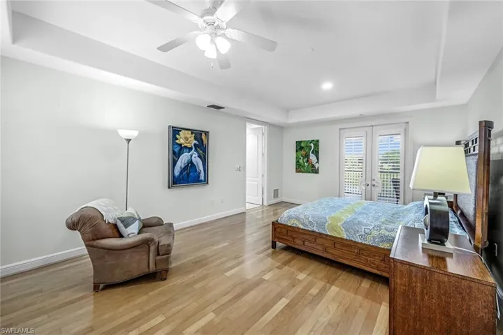 Bedroom featuring a tray ceiling, light wood-style floors, access to outside, recessed lighting, and a ceiling fan
