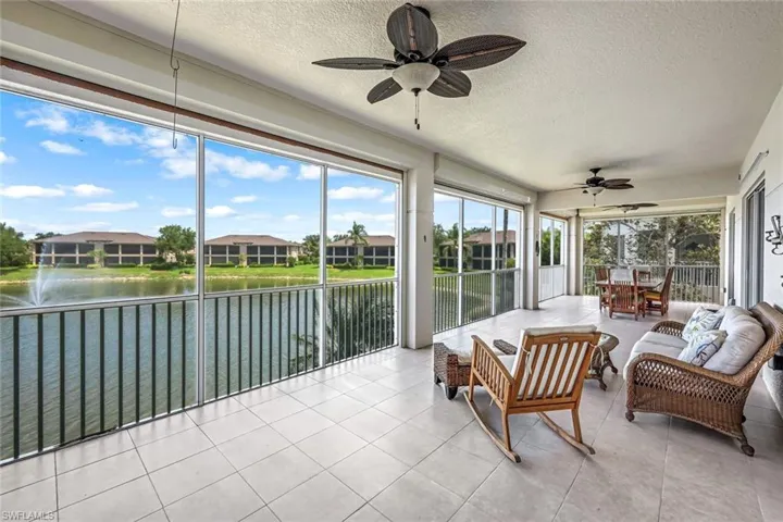 Sunroom featuring a water view, tile patterned floors, and a textured ceiling