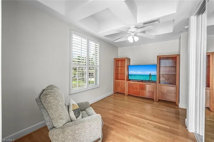 Sitting room with light wood finished floors, coffered ceiling, and a ceiling fan