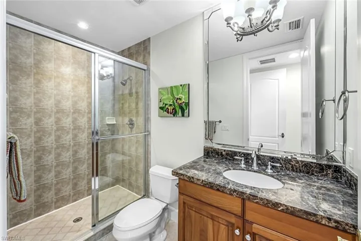 Bathroom featuring a stall shower, vanity, and a chandelier