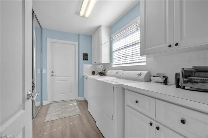 Laundry room is bright and has plenty of extra cabinets and a closet.