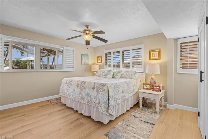 Bedroom featuring ceiling fan, light wood-type flooring, and a textured ceiling