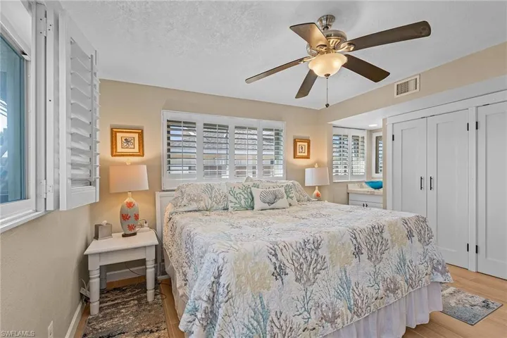 Bedroom with a textured ceiling, light hardwood / wood-style flooring, and ceiling fan
