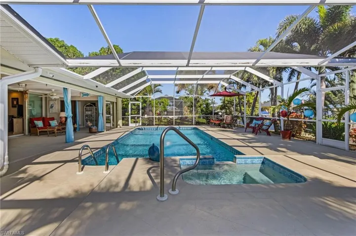 View of pool with glass enclosure, ceiling fan, and a patio