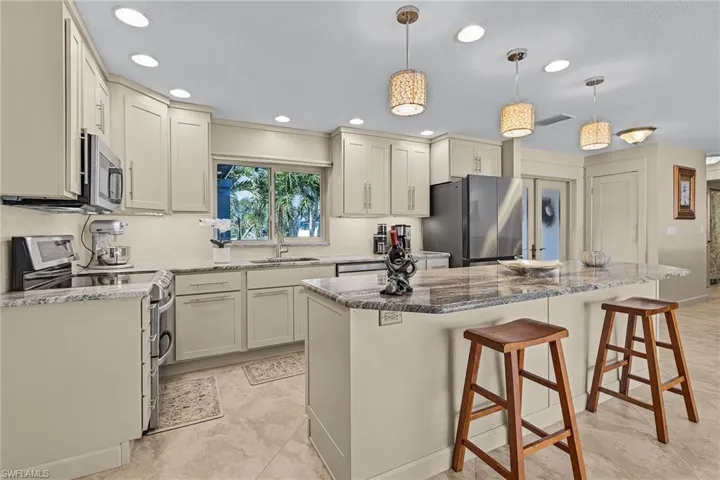 Kitchen featuring pendant lighting, sink, appliances with stainless steel finishes, a kitchen island, and a breakfast bar area