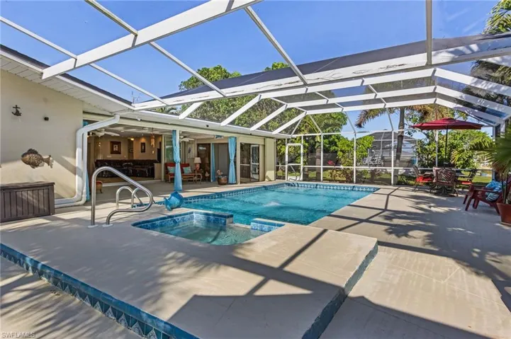 View of pool featuring a patio area, a lanai, an outdoor bar, and an in ground hot tub