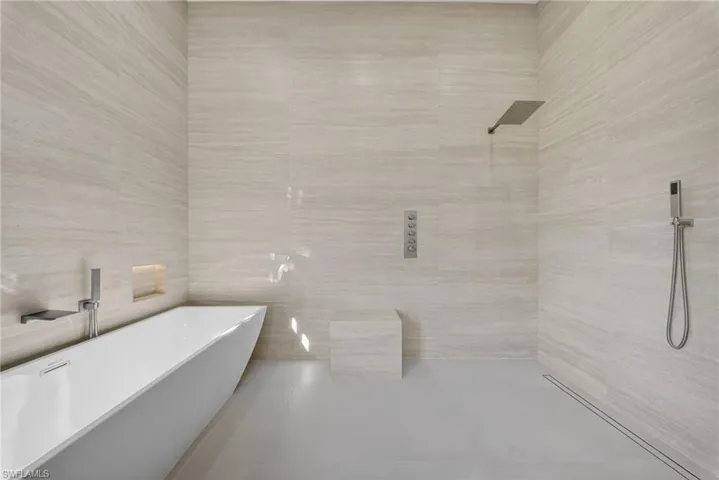 Bathroom featuring a soaking tub, tile walls, and tiled shower