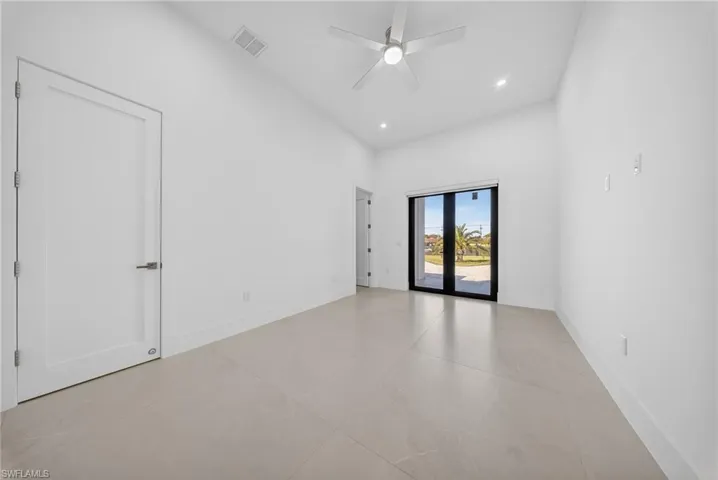 Empty room featuring a ceiling fan, a high ceiling, french doors, and recessed lighting