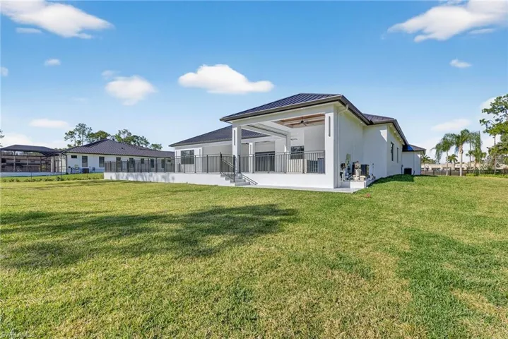 Back of house featuring a patio, a standing seam roof, a yard, and a ceiling fan