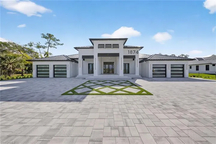 View of front of house with a standing seam roof, an attached garage, french doors, driveway, and stucco siding