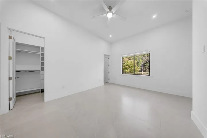 Unfurnished bedroom featuring a spacious closet, a ceiling fan, and recessed lighting
