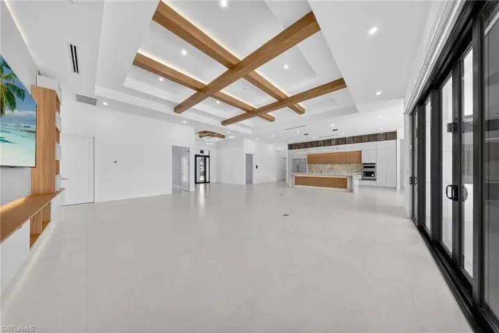 Unfurnished living room with coffered ceiling, recessed lighting, and a raised ceiling