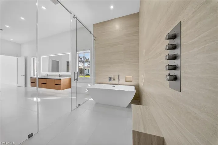 Bathroom with vanity, tile walls, a freestanding bath, light tile patterned flooring, and a shower stall