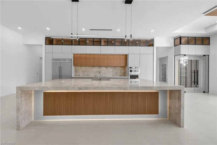 Dual tone kitchen featuring modern cabinets, light stone countertops, decorative light fixtures, and dual tone cabinets