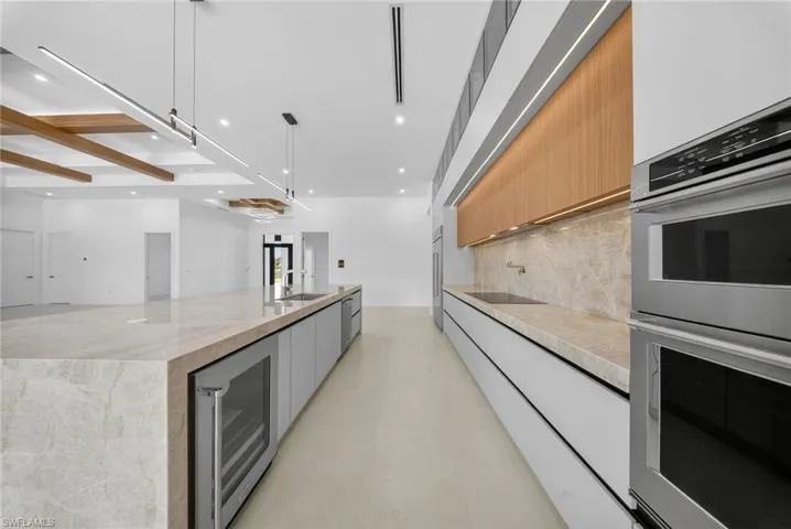 Two tone kitchen with stainless steel appliances, modern cabinets, beverage cooler, a spacious island, and two tone cabinets
