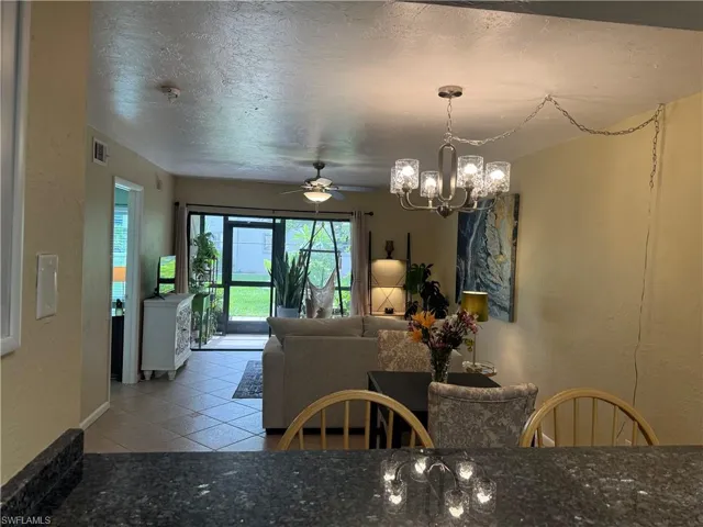 Tiled dining area featuring a textured ceiling and ceiling fan with notable chandelier