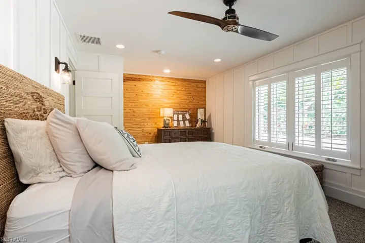 Carpeted bedroom with recessed lighting, a decorative wall, a ceiling fan, and wood walls