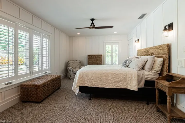 Bedroom featuring a decorative wall, carpet floors, and a ceiling fan