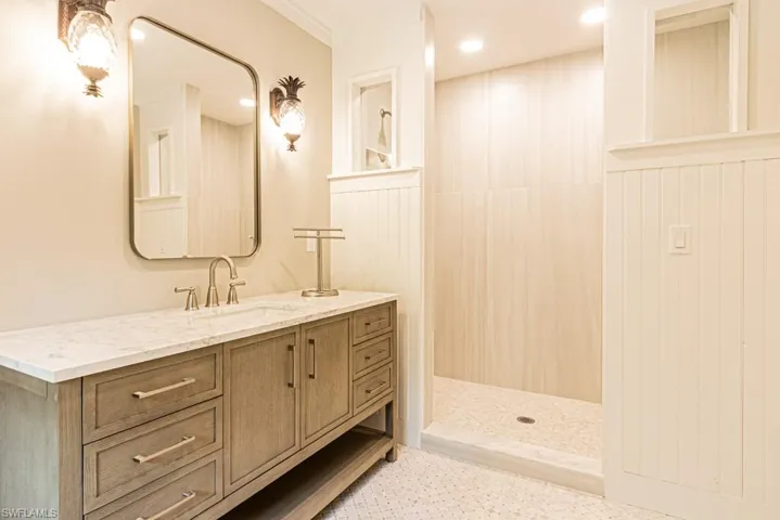 Bathroom with vanity, tiled shower, and crown molding