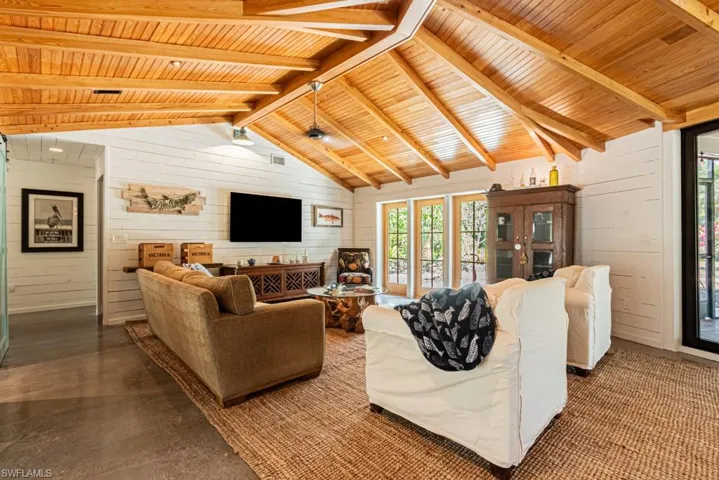 Living area with wooden ceiling, plenty of natural light, wooden walls, and finished concrete flooring