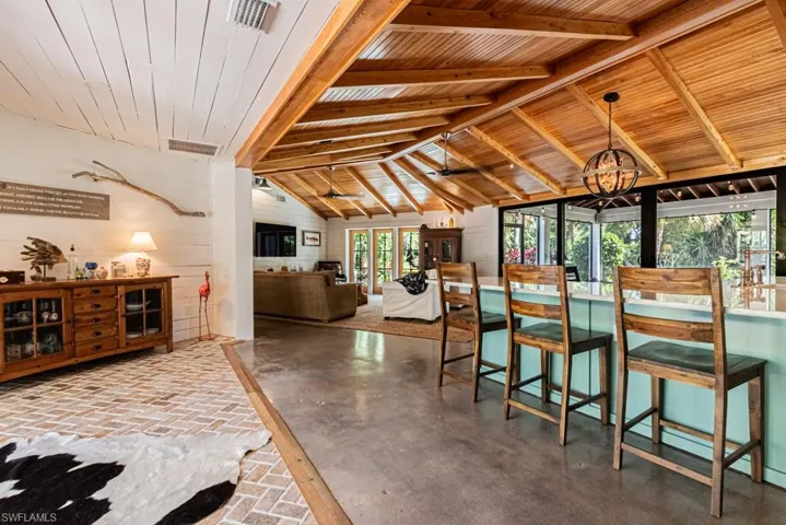 Dining area with vaulted ceiling, wooden walls, a chandelier, and wood ceiling