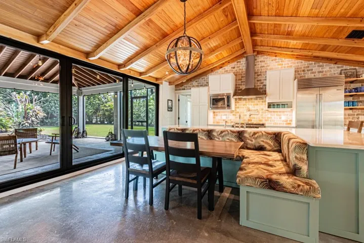 Dining area with wooden ceiling, brick wall, a chandelier, and finished concrete flooring