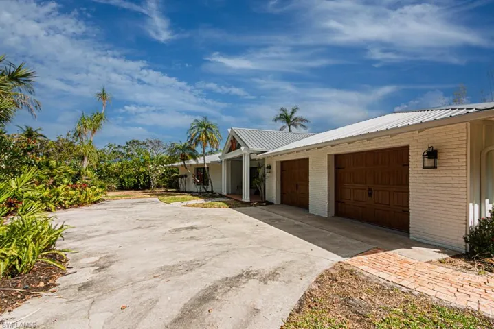 View of front facade with brick siding, concrete driveway, metal roof, and a garage