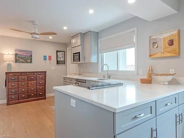 Kitchen with gray cabinetry, a ceiling fan, light wood-style flooring, light stone counters, and recessed lighting