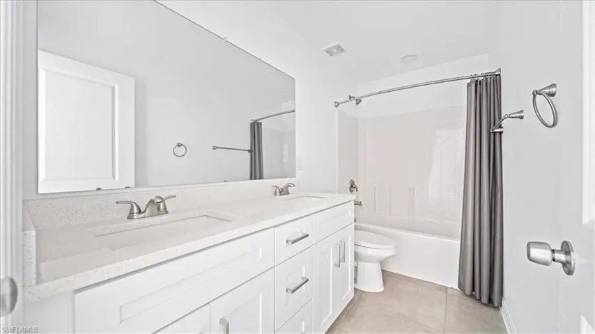 Full bathroom featuring shower / bath combo, double vanity, and light tile patterned flooring