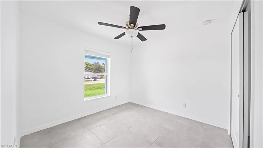 Empty room with ceiling fan and light tile patterned floors