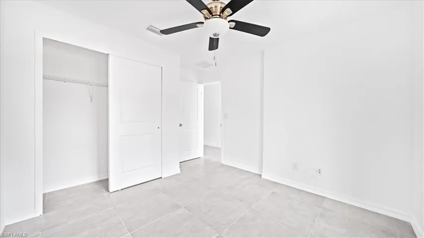 Unfurnished bedroom with a ceiling fan, a closet, and light tile patterned floors