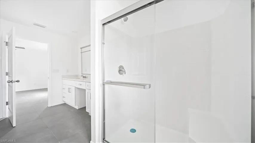 Full bathroom with vanity, a shower stall, and dark tile patterned floors