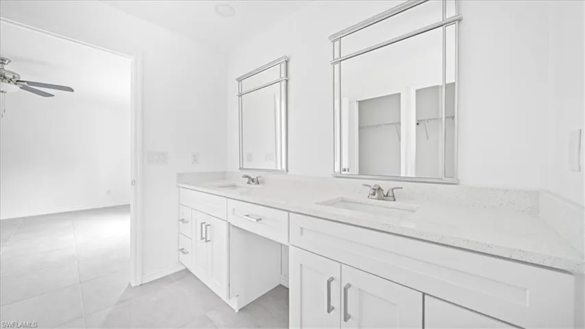 Bathroom featuring double vanity, light tile patterned floors, and ceiling fan