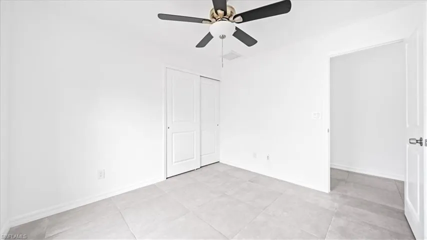 Unfurnished bedroom featuring a ceiling fan, a closet, and light tile patterned floors