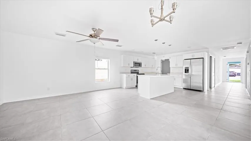 Kitchen with white cabinets, open floor plan, stainless steel appliances, light countertops, and a chandelier