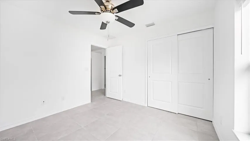 Unfurnished bedroom with ceiling fan, light tile patterned floors, and a closet
